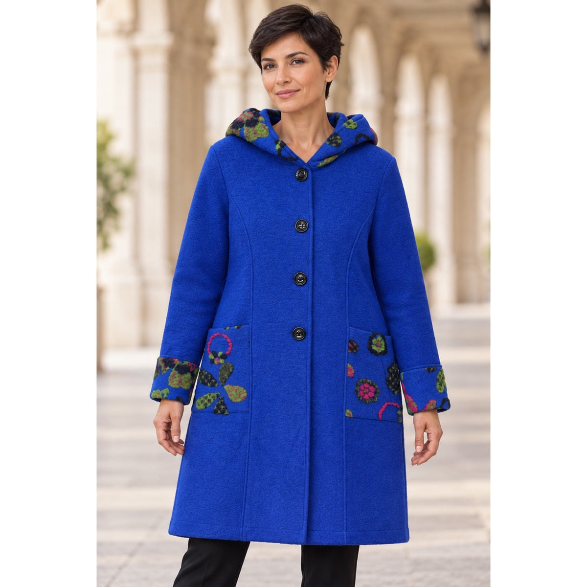 Modelo con abrigo azul eléctrico con capucha, botones y detalles florales en bolsillos y puños, vista delantera - POLITA 148299025.