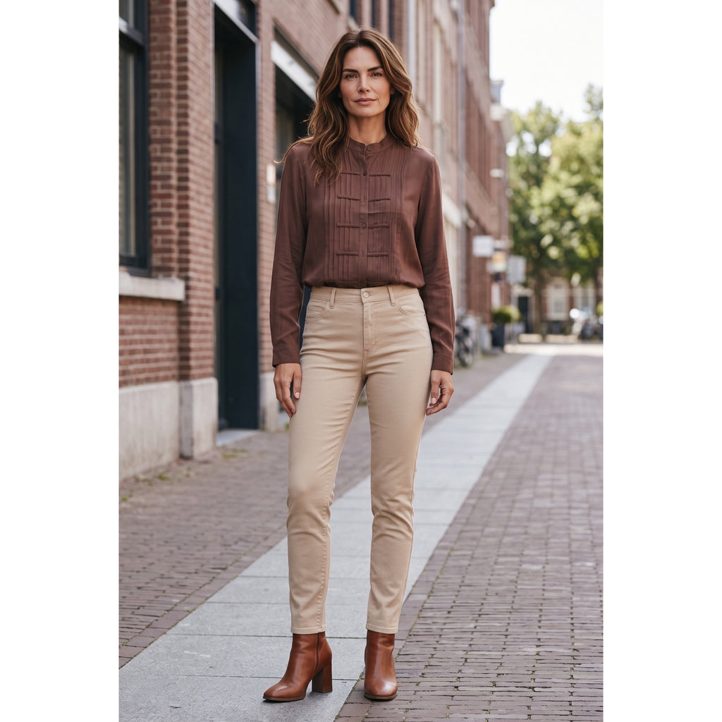Modelo con blusa marrón de cuello mao y alforzas, llevada por dentro de un pantalón beige.