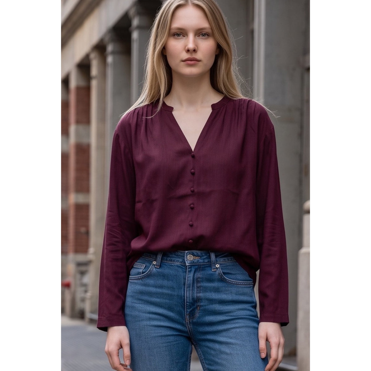 Detalle de la blusa burdeos con escote en pico, botones forrados y frunces en los hombros.