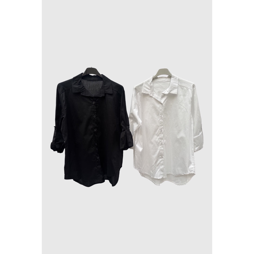 Camisas en negro y blanco con cuello clásico, botones al tono, mangas remangables y bajo redondeado.