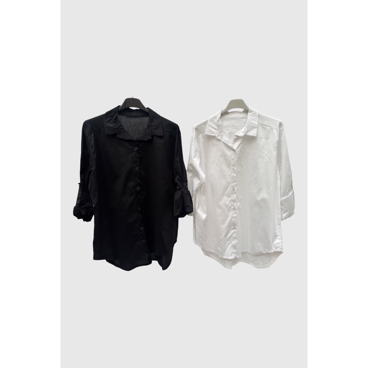 Camisas en negro y blanco con cuello clásico, botones al tono, mangas remangables y bajo redondeado.