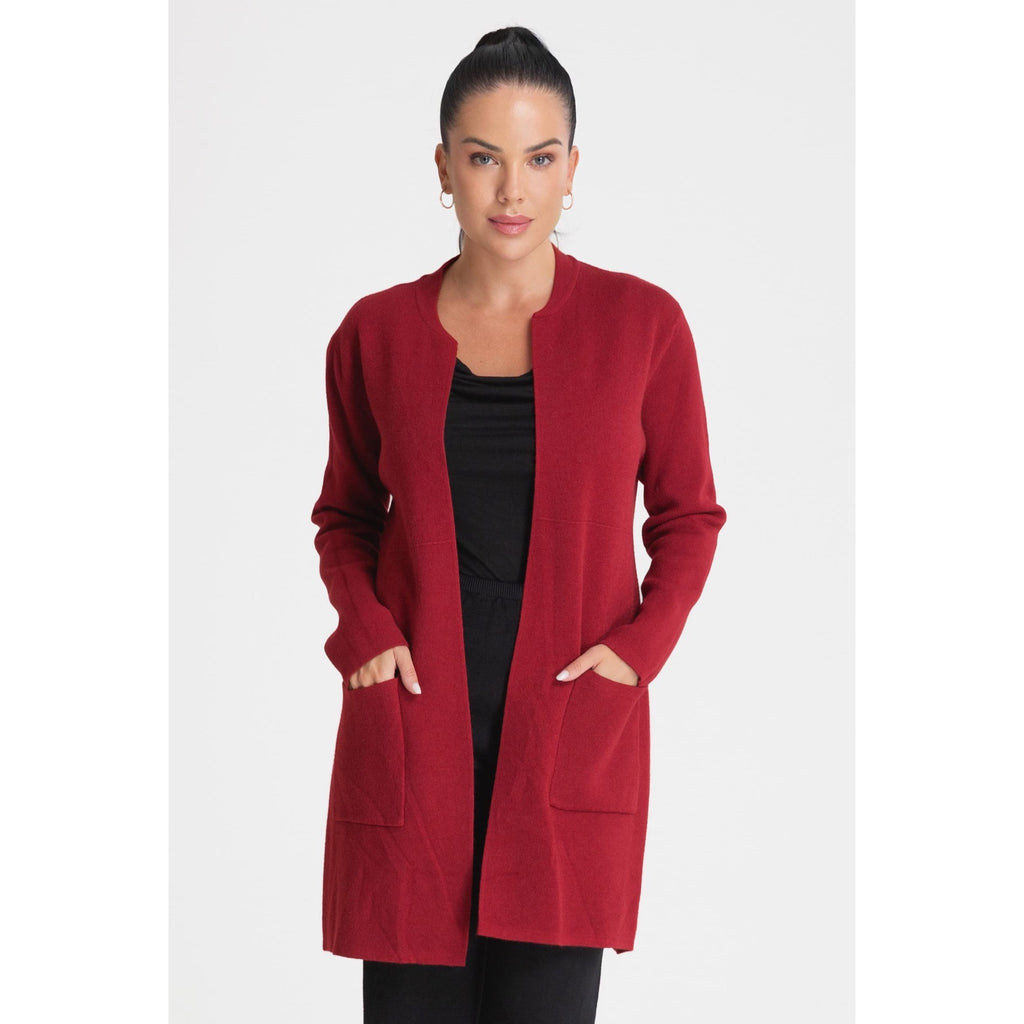Modelo con cárdigan largo rojo de punto abierto y bolsillos de parche, combinado con prendas negras.