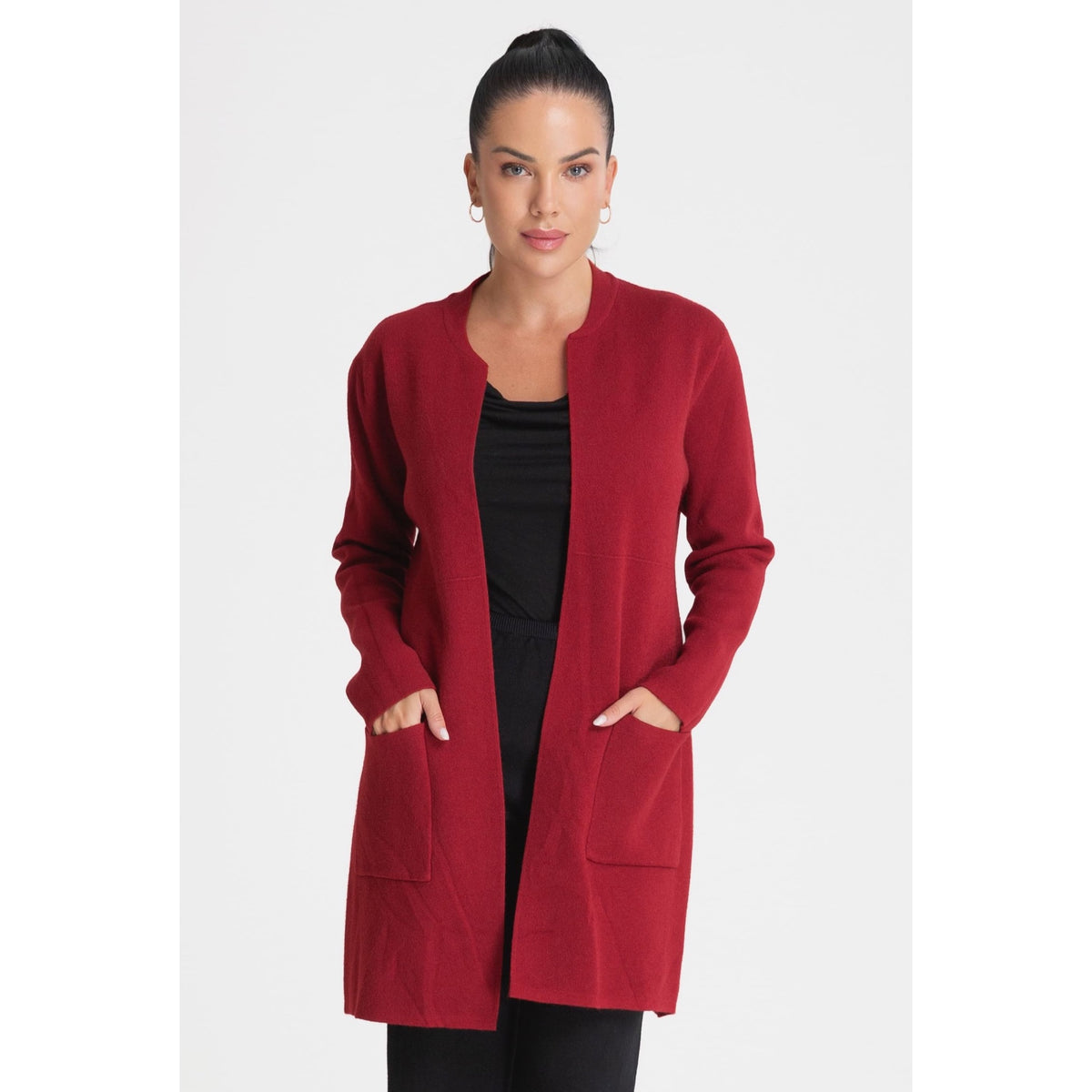 Modelo con cárdigan largo rojo de punto abierto y bolsillos de parche, combinado con prendas negras.