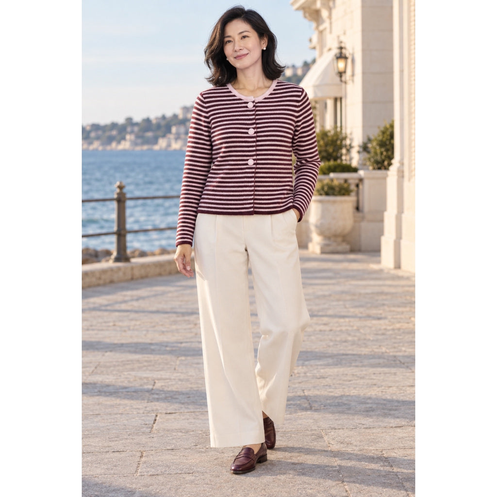 Modelo con cárdigan de rayas burdeos y rosa, cuello redondo y botones rosas, combinado con pantalón marfil.