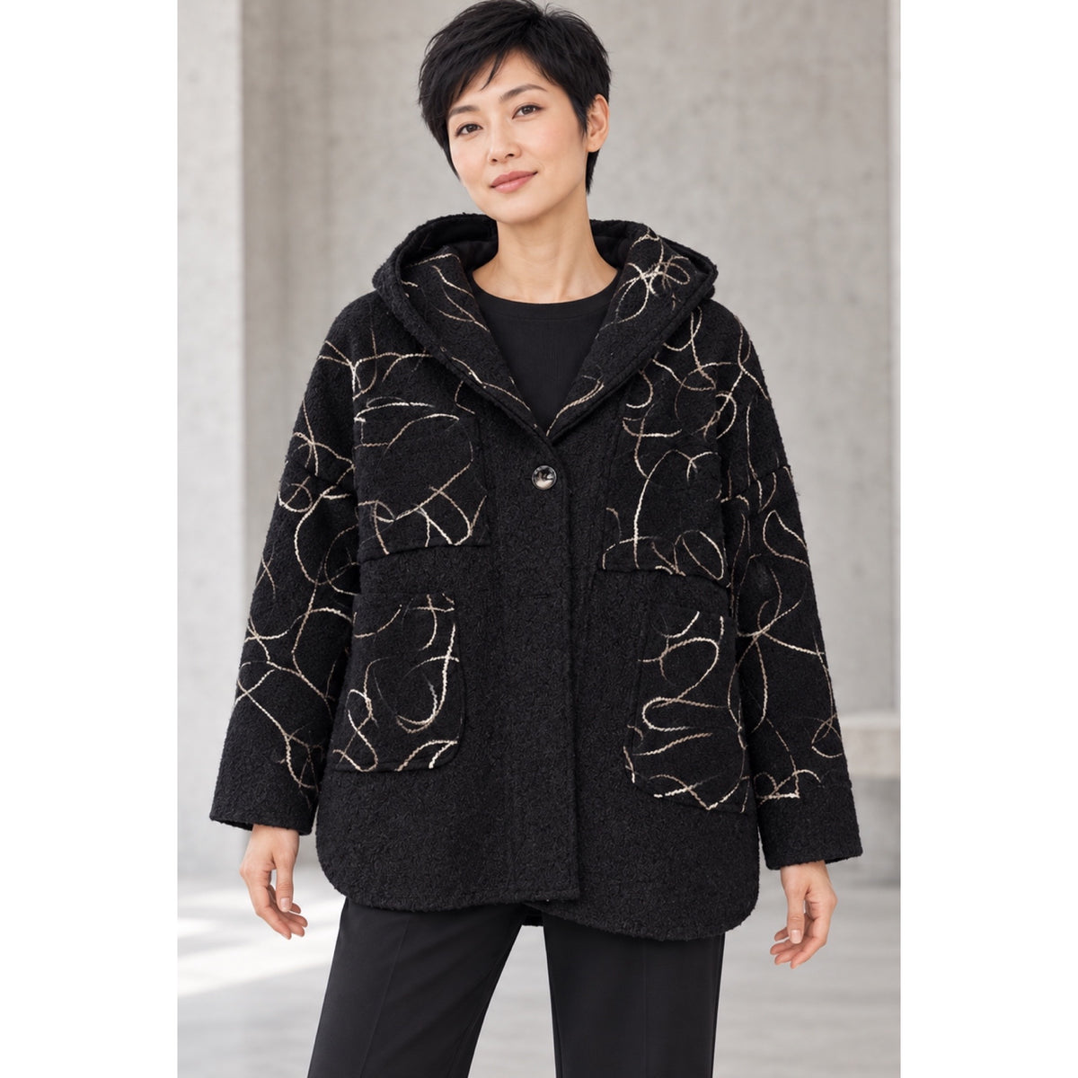 Modelo con chaqueta negra de capucha, líneas curvas claras a contraste y bolsillos de parche - POLITA 148299367A.