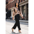 Modelo con conjunto de seda formado por blusa de estampado marmoleado en beige y tonos oscuros y pantalón palazzo negro.