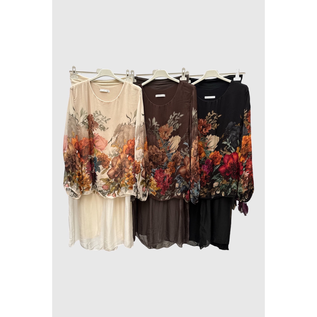 Conjuntos de seda en crema, choco y negro, con blusas de estampado floral multicolor y pantalones lisos.