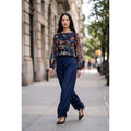 Modelo con conjunto de seda azul marino, blusa de flores multicolor con mangas semitransparentes y pantalón palazzo liso.