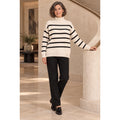 Modelo con jersey crudo de punto texturizado, rayas negras y cuello alto, combinado con pantalón negro.
