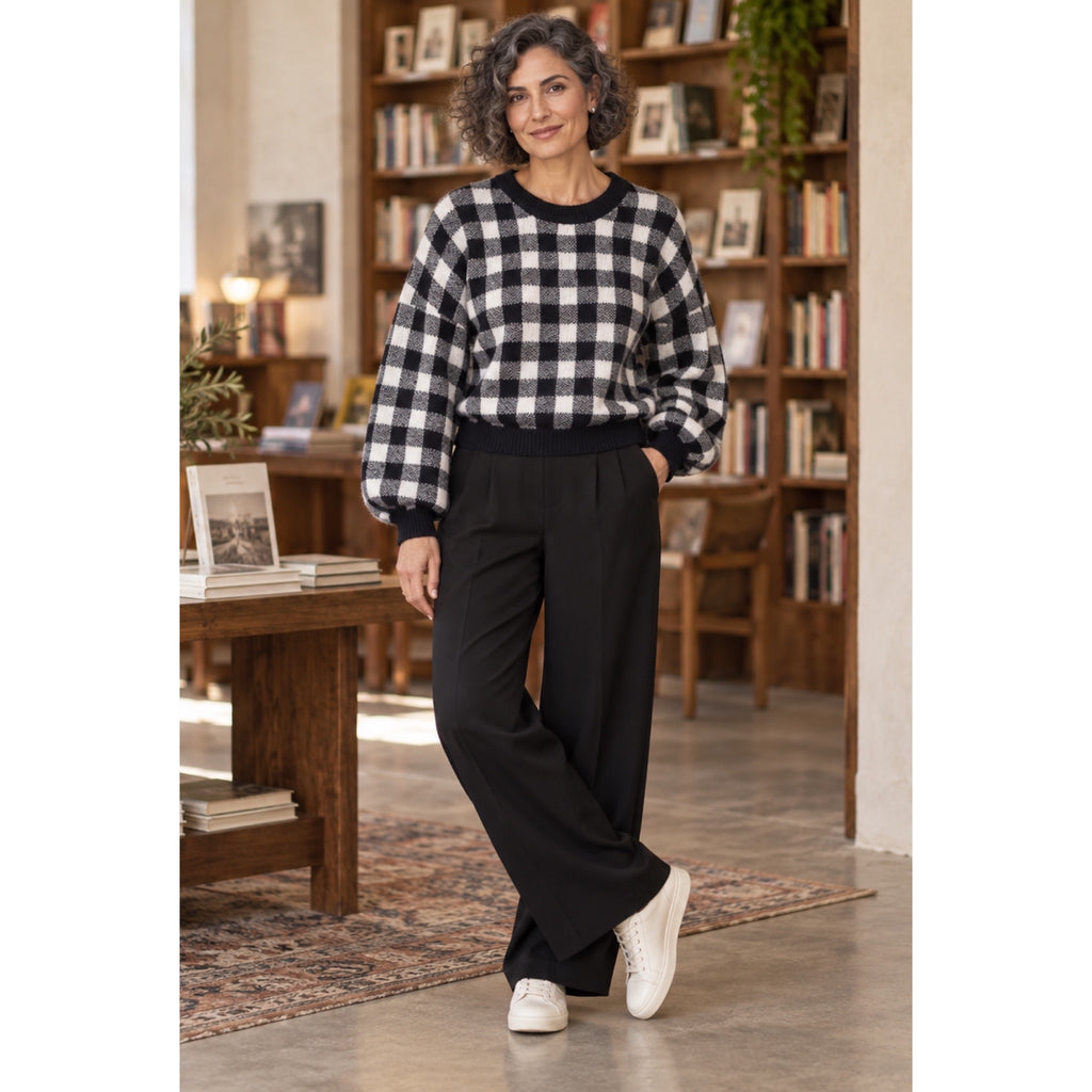 Modelo con jersey de cuadros negros y blancos, cuello redondo y mangas abullonadas, combinado con pantalón negro.