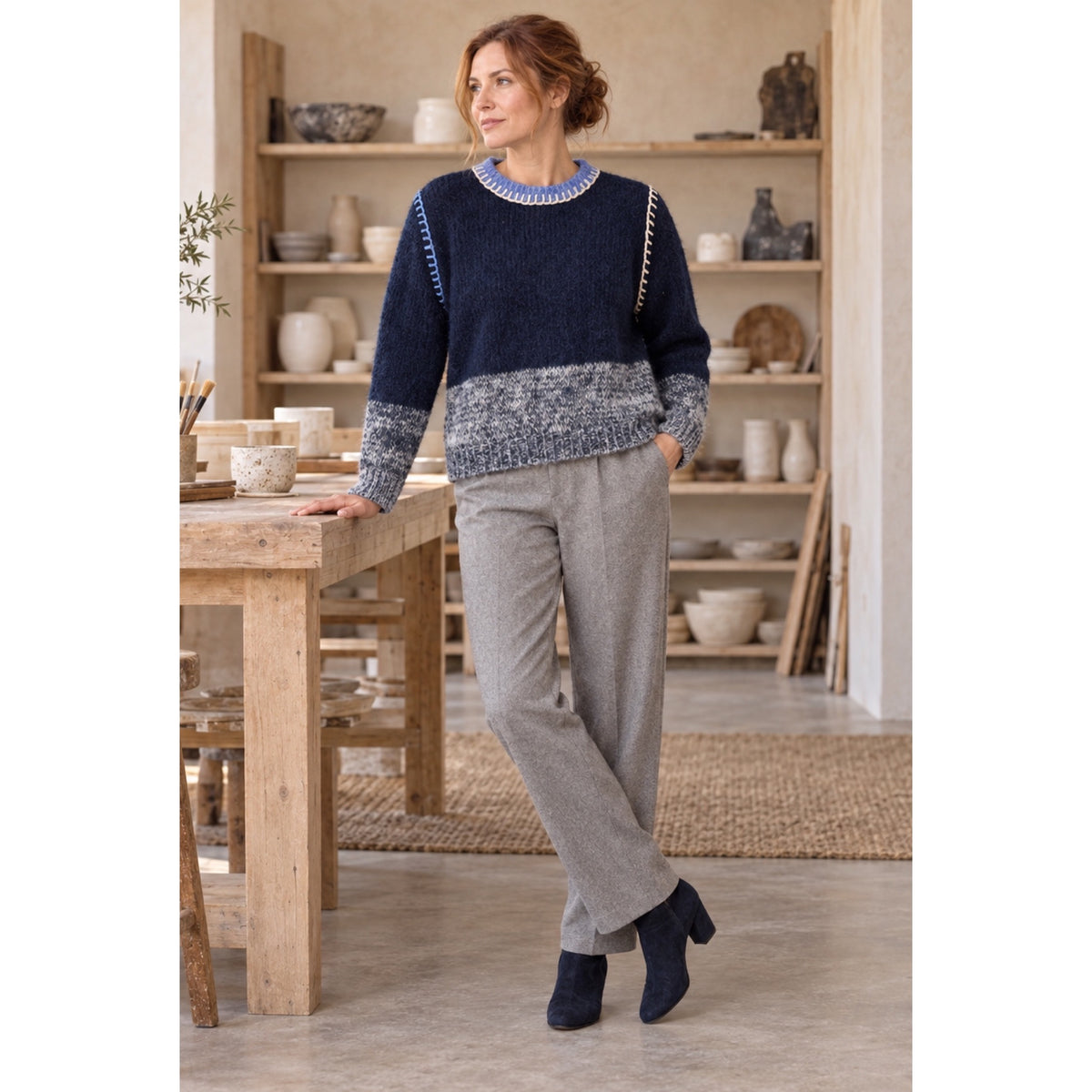 Modelo con jersey azul marino, bajo y puños jaspeados y pespuntes a contraste, combinado con pantalón gris.