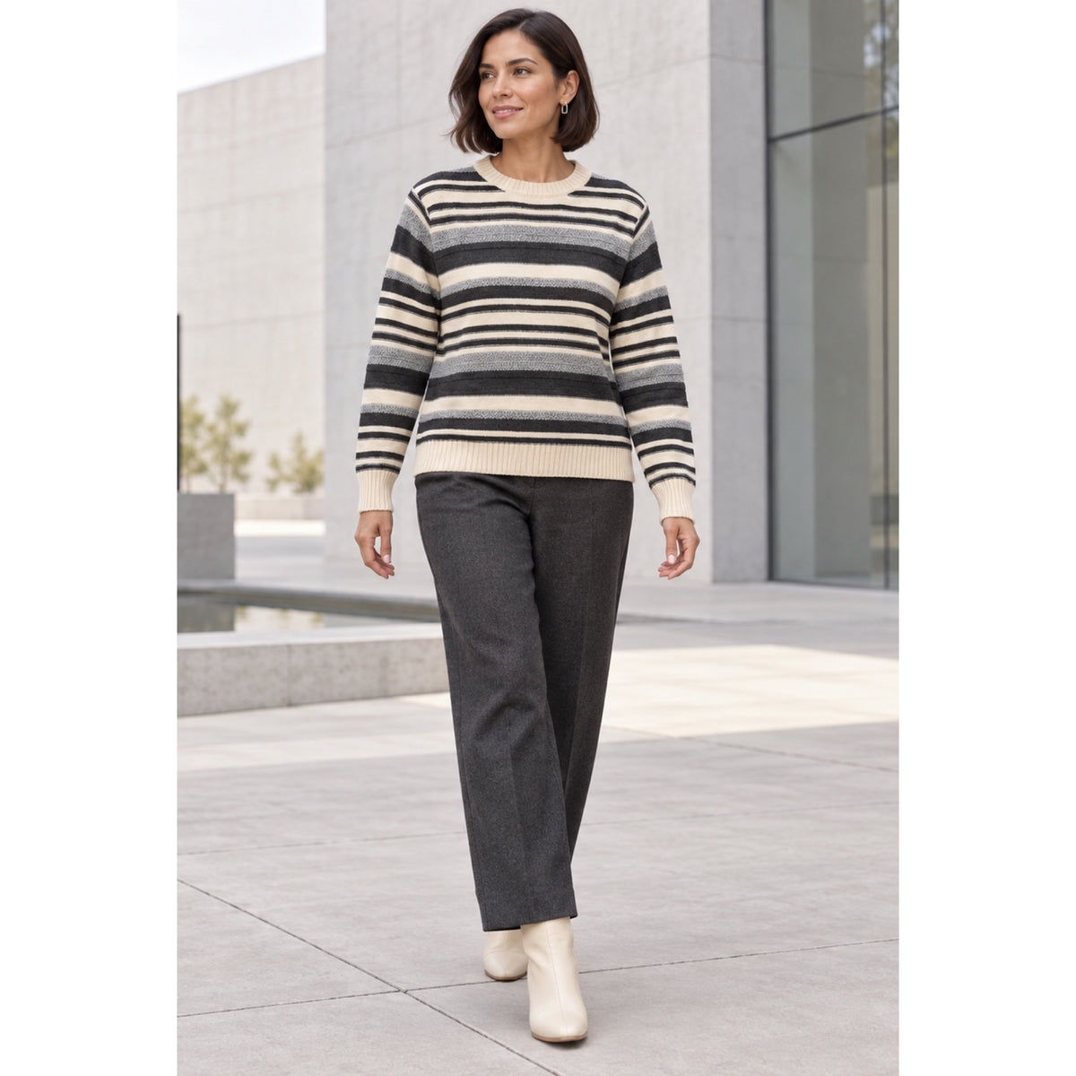Modelo con jersey de rayas crema, gris y antracita, con cuello redondo y puños de canalé, combinado con pantalón gris.