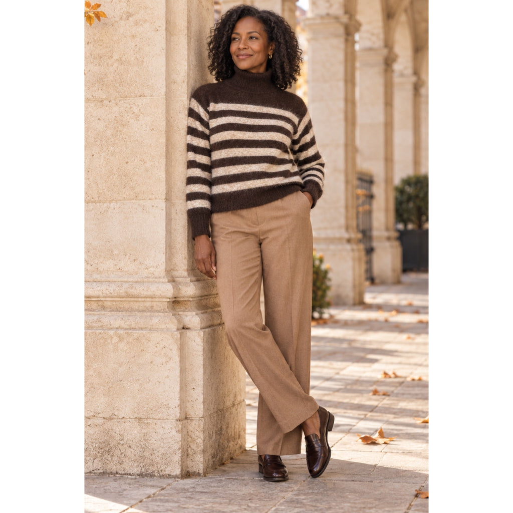 Modelo con jersey de cuello alto marrón chocolate y rayas beige, combinado con pantalón camel.