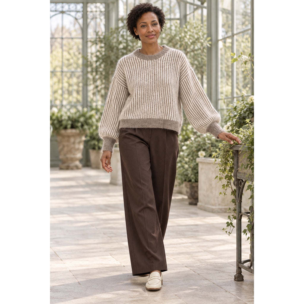Modelo con jersey taupe y crudo de rayas verticales, cuello redondo y mangas abullonadas, combinado con pantalón marrón.