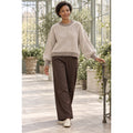 Modelo con jersey taupe y crudo de rayas verticales, cuello redondo y mangas abullonadas, combinado con pantalón marrón.