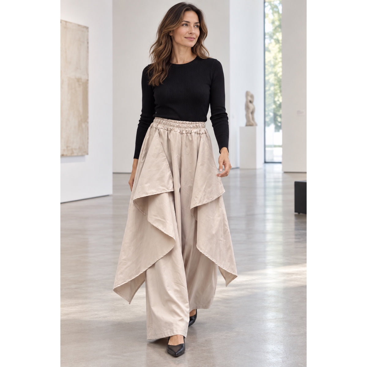 Modelo con pantalón efecto trench beige de pierna ancha, cintura elástica y paneles asimétricos superpuestos - POLITA 141468150.