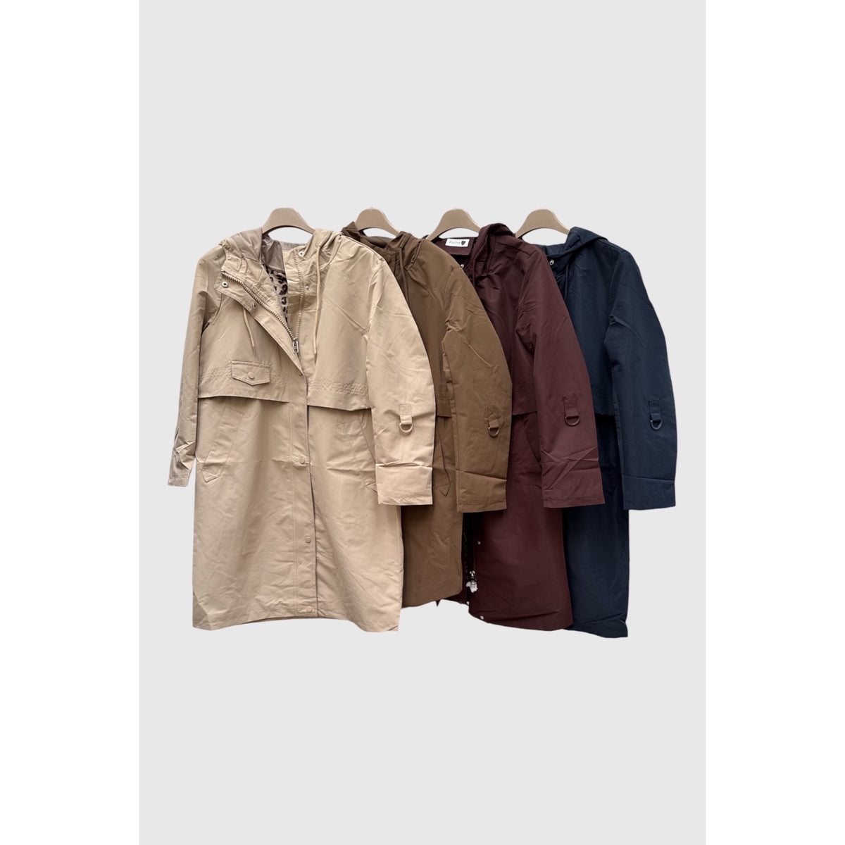Parkas largas con capucha y bolsillos en beige, marrón, burdeos y azul marino, presentadas en perchas.